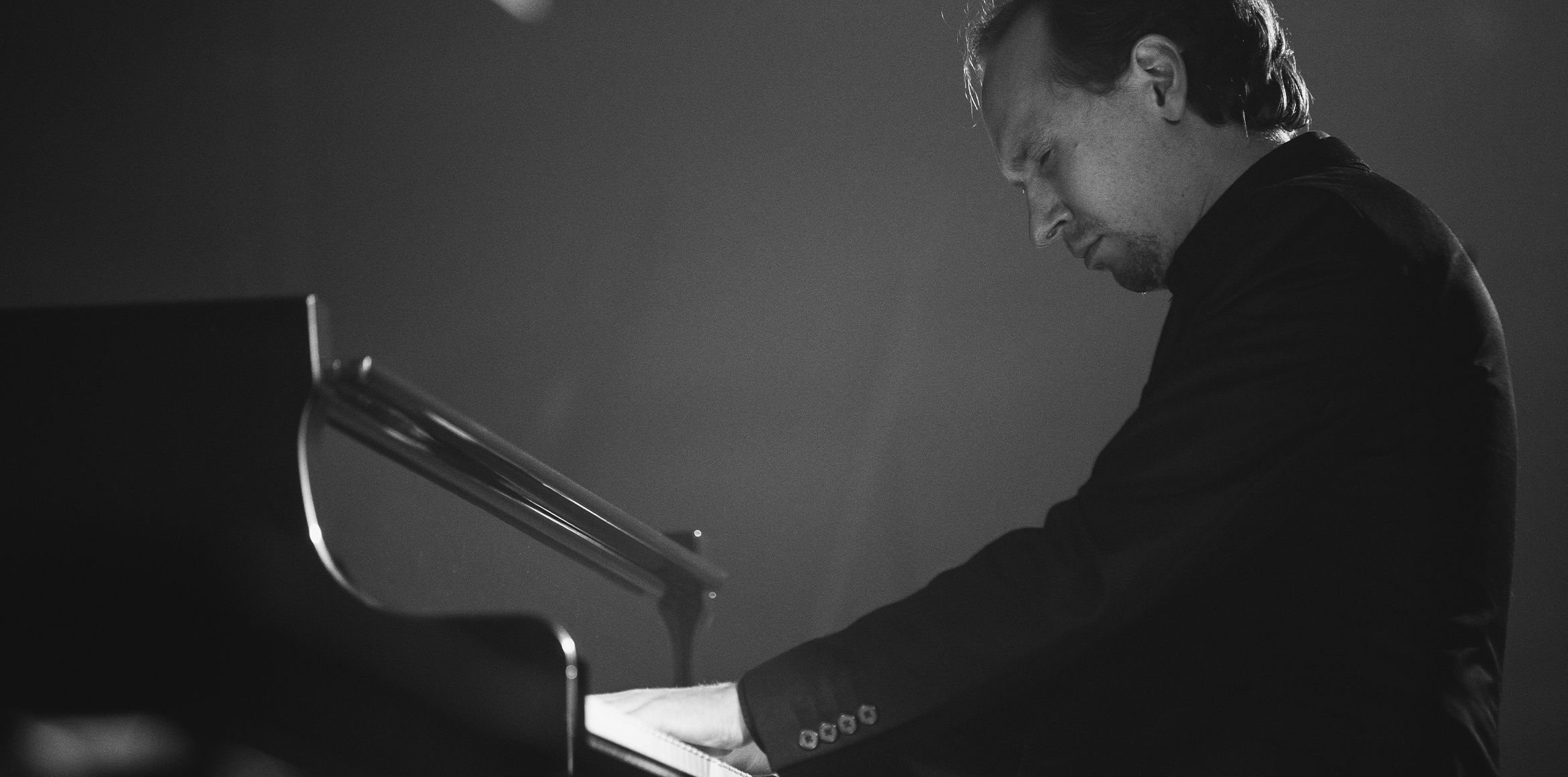 Composer Alexey Kurbatov playing the piano black and white